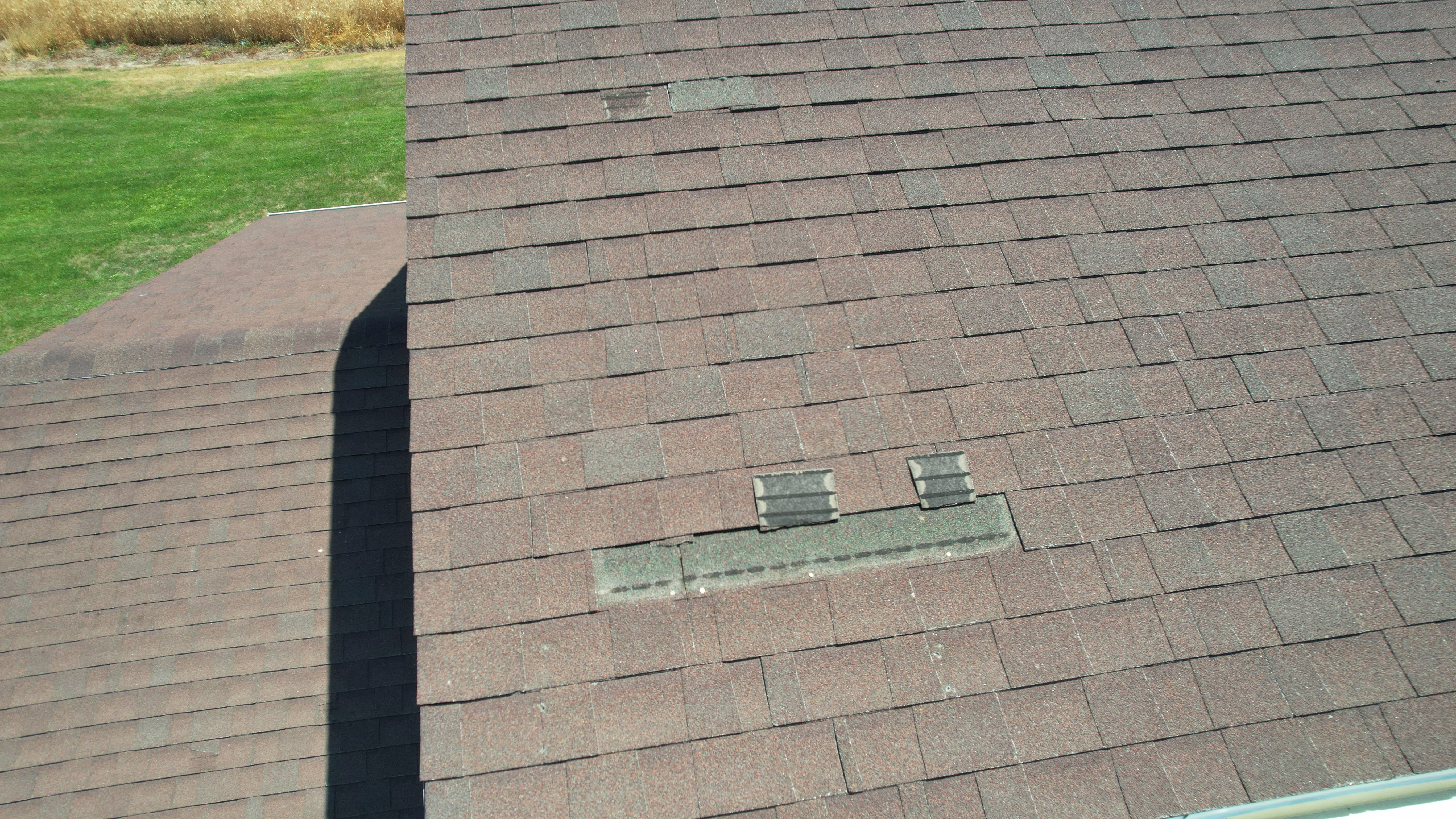 A roof with wind damage before restoration by Robinhood Roofing.